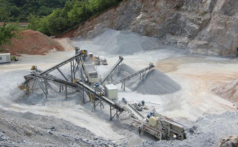Heavy mining machinery including crushers, conveyors, and loaders at a quarry