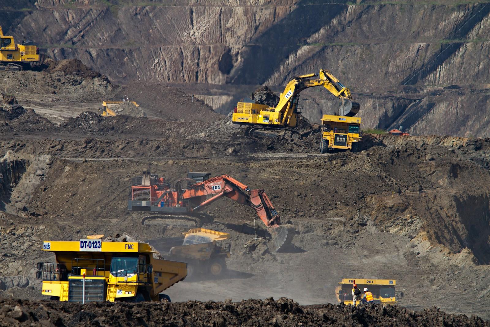 Excavators and haul trucks working in an open-pit mine in Odisha