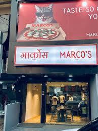 Marco's restaurant storefront and illuminated signage at night